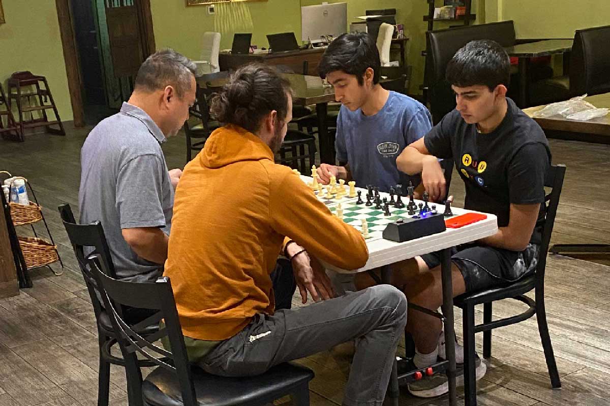 Four guys playing chess at Delciano