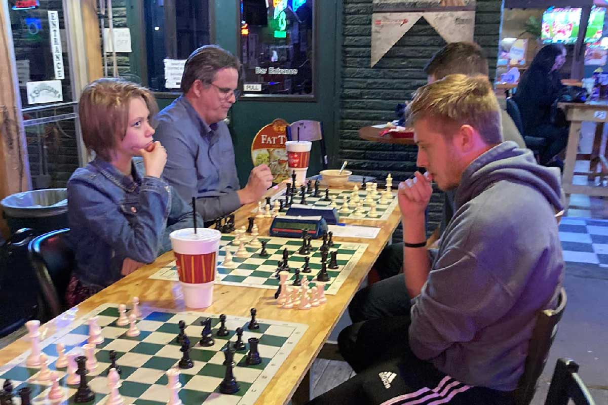 A young lady and a young man playing chess